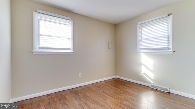 spare room with visible vents, baseboards, a healthy amount of sunlight, and wood finished floors