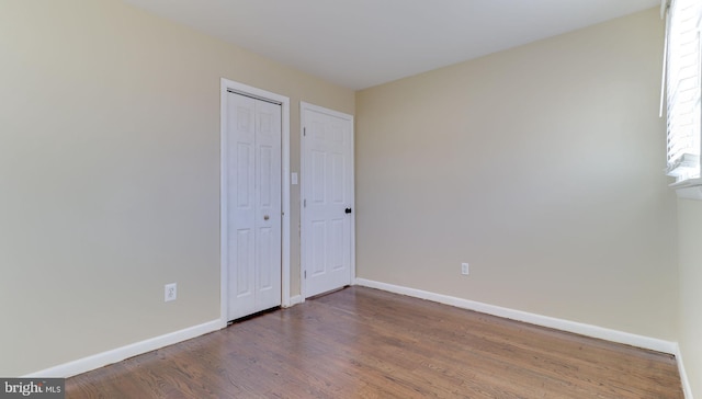 unfurnished bedroom with wood finished floors, baseboards, and a closet