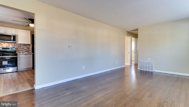 unfurnished room featuring visible vents, baseboards, wood finished floors, and a ceiling fan