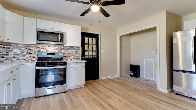 kitchen with stainless steel appliances, white cabinetry, backsplash, and light countertops