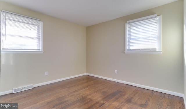 spare room featuring visible vents, baseboards, and wood finished floors