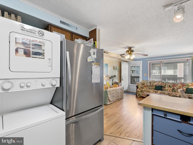 kitchen with visible vents, stacked washer and dryer, blue cabinetry, freestanding refrigerator, and light countertops