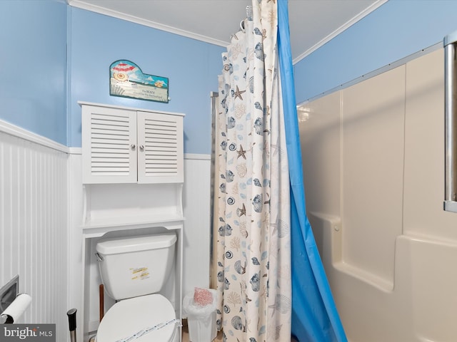 bathroom with a shower with curtain, toilet, wainscoting, and crown molding