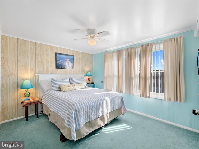 carpeted bedroom featuring ceiling fan, wood walls, baseboards, and ornamental molding