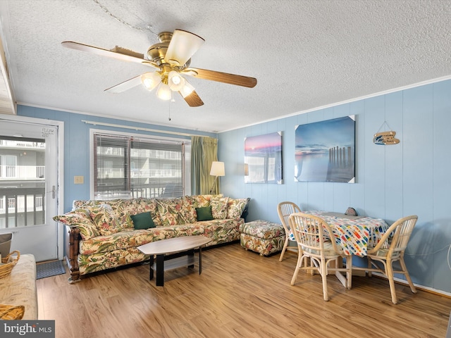 living area featuring a textured ceiling, wood finished floors, a ceiling fan, and ornamental molding