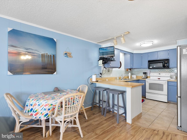 kitchen featuring white electric range oven, a peninsula, a sink, black microwave, and blue cabinets