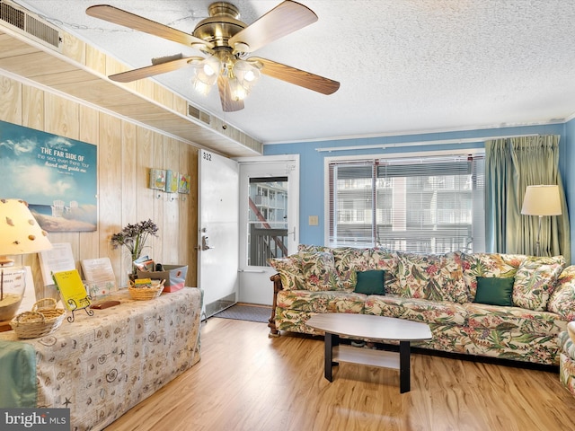 living room with visible vents, a textured ceiling, wood finished floors, and a ceiling fan