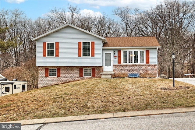 tri-level home with brick siding, a front yard, and entry steps