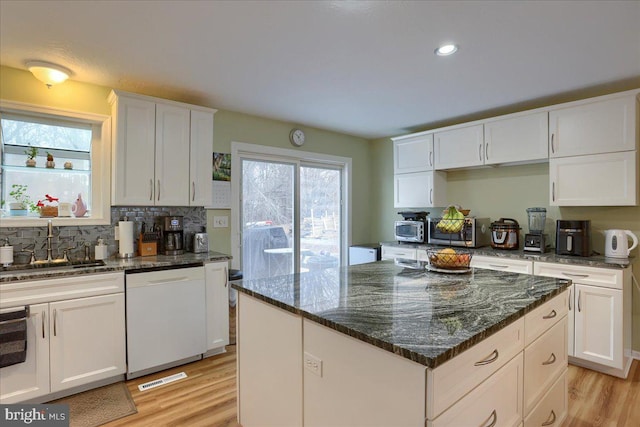 kitchen with a sink, light wood-style flooring, white cabinetry, and white dishwasher