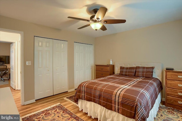 bedroom with light wood-style flooring, baseboards, multiple closets, and a ceiling fan