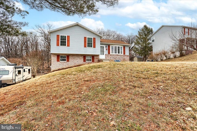 tri-level home featuring brick siding and a front yard