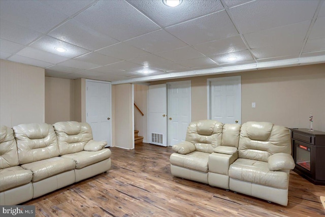 living area featuring stairs, wood finished floors, visible vents, and a paneled ceiling