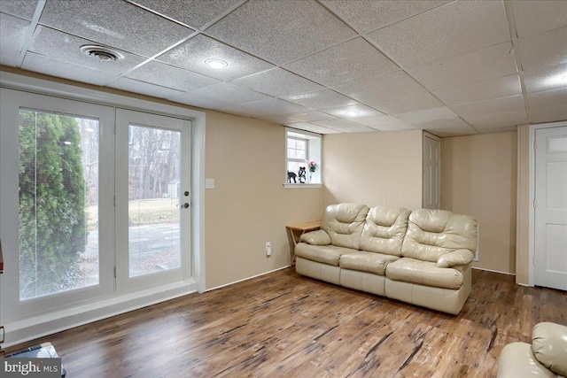 living room featuring visible vents, a drop ceiling, baseboards, and wood finished floors