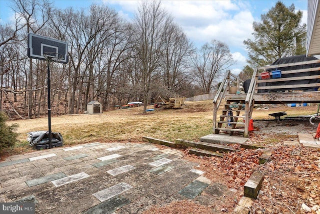 view of yard featuring an outbuilding, stairway, a storage unit, and a patio area