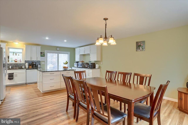 dining area with recessed lighting, baseboards, light wood-style floors, and an inviting chandelier