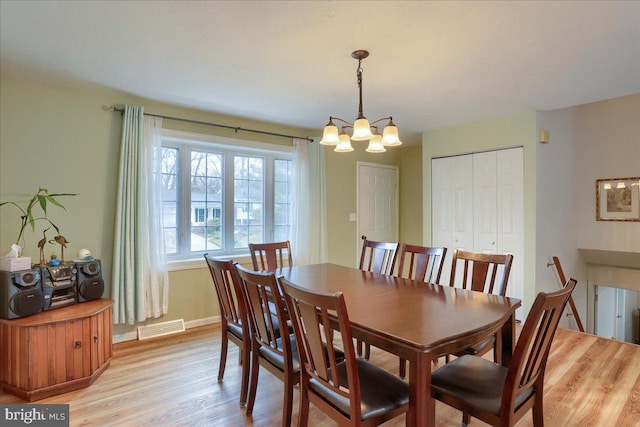 dining room with visible vents, light wood-style flooring, baseboards, and an inviting chandelier