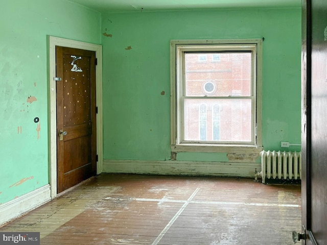 empty room with hardwood / wood-style floors and radiator heating unit