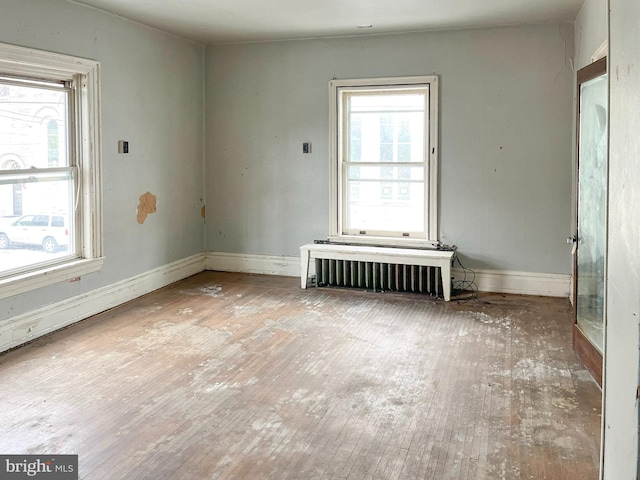 spare room featuring radiator, wood finished floors, and baseboards