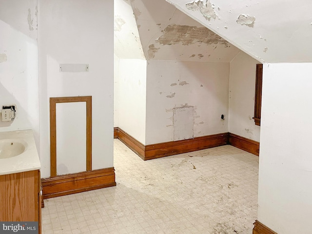 additional living space with tile patterned floors, a sink, baseboards, and vaulted ceiling