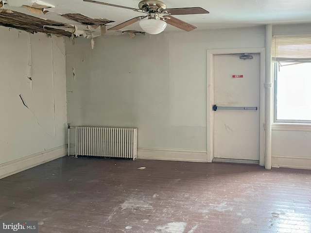 empty room featuring radiator, a ceiling fan, and baseboards