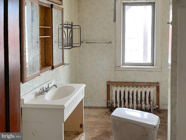 bathroom featuring vanity, toilet, radiator, and wallpapered walls