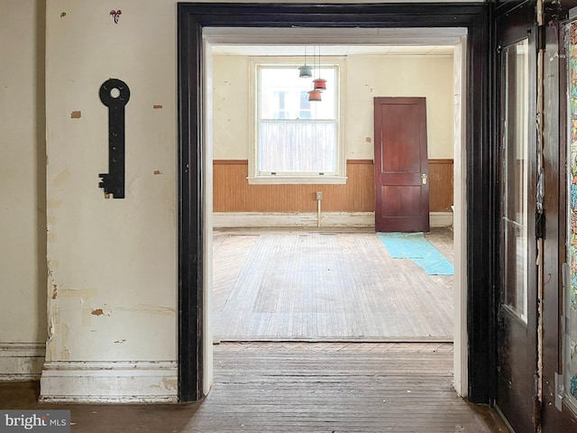 interior space with wooden walls, wood finished floors, and wainscoting