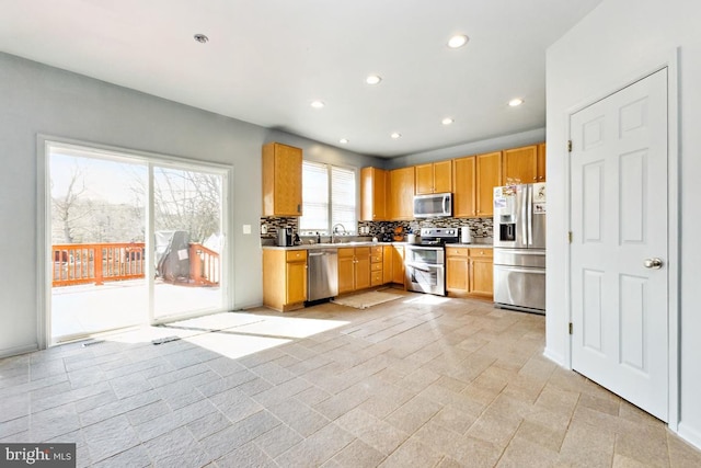 kitchen with a sink, recessed lighting, appliances with stainless steel finishes, light countertops, and decorative backsplash