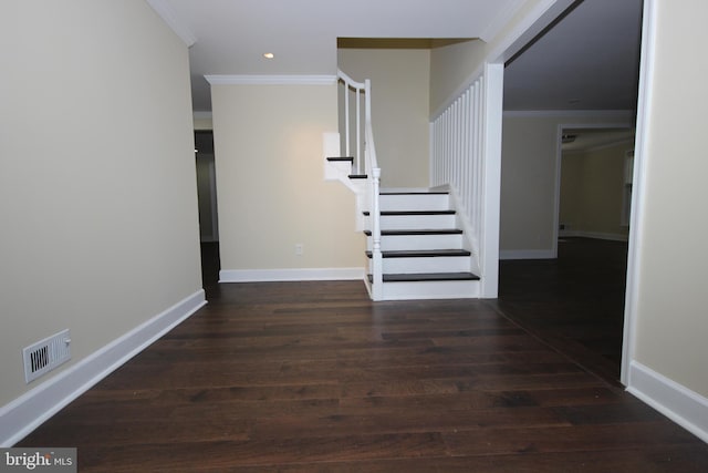 hallway with wood finished floors, baseboards, visible vents, ornamental molding, and stairs