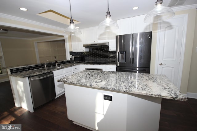 kitchen with dark wood finished floors, ornamental molding, stainless steel appliances, under cabinet range hood, and tasteful backsplash