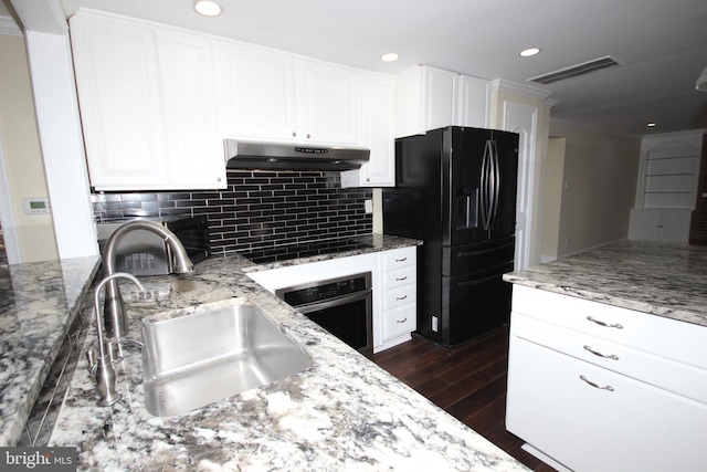 kitchen with light stone countertops, visible vents, a sink, black appliances, and under cabinet range hood