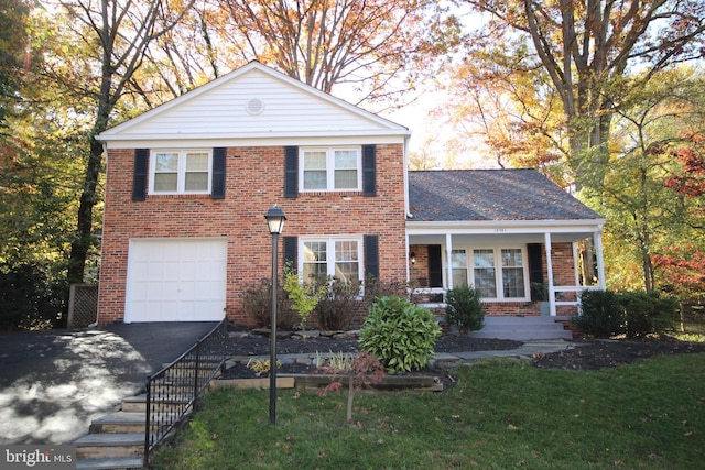 traditional home with a porch, a garage, brick siding, and driveway