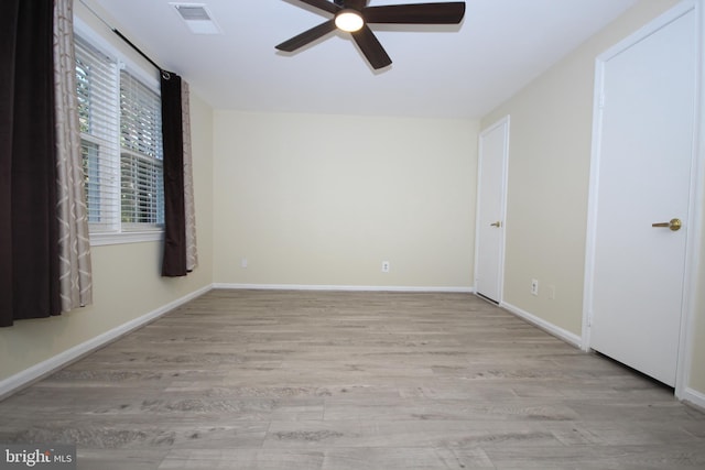 spare room with visible vents, wood finished floors, baseboards, and ceiling fan