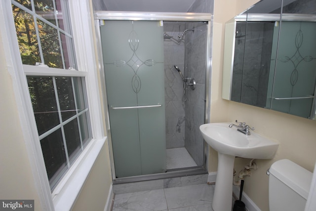 bathroom featuring toilet, marble finish floor, a stall shower, a sink, and baseboards