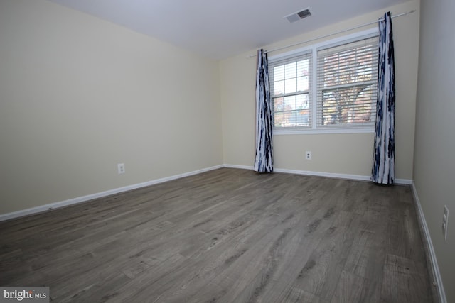 spare room with visible vents, baseboards, and wood finished floors