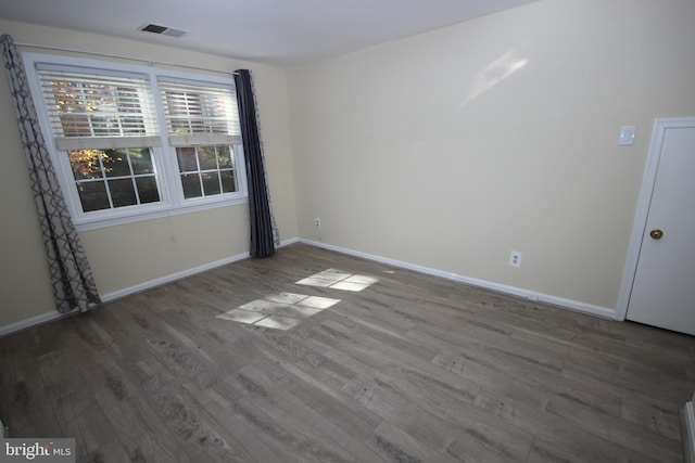 unfurnished room with visible vents, baseboards, and wood finished floors