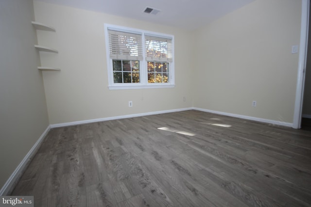 empty room with visible vents, baseboards, and wood finished floors