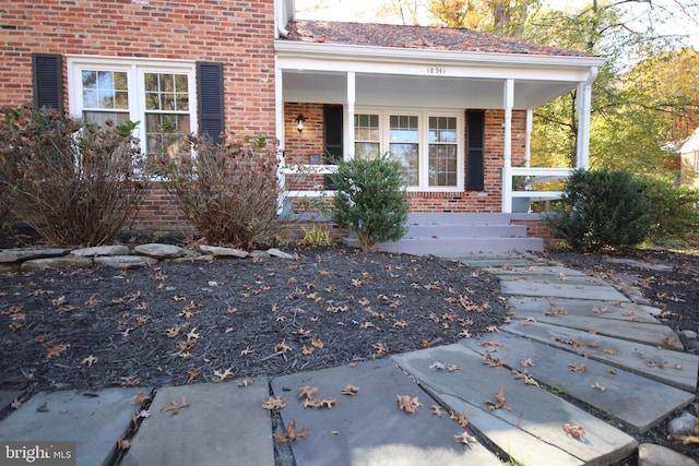 property entrance with covered porch and brick siding