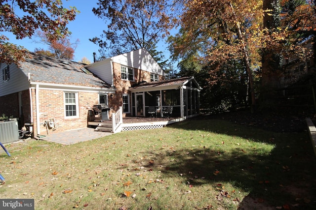 rear view of property featuring central air condition unit, a yard, a sunroom, brick siding, and a patio area