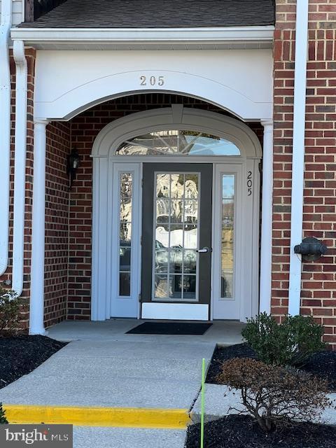 entrance to property with brick siding and roof with shingles