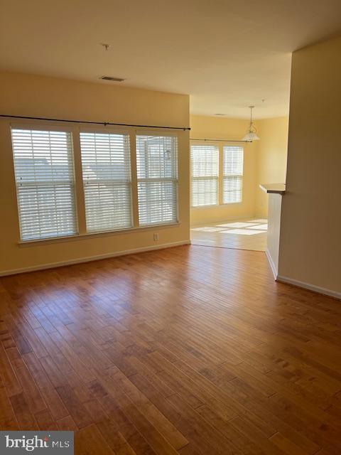 spare room featuring wood finished floors, visible vents, and baseboards