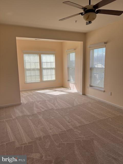 unfurnished room with light carpet, plenty of natural light, and a ceiling fan