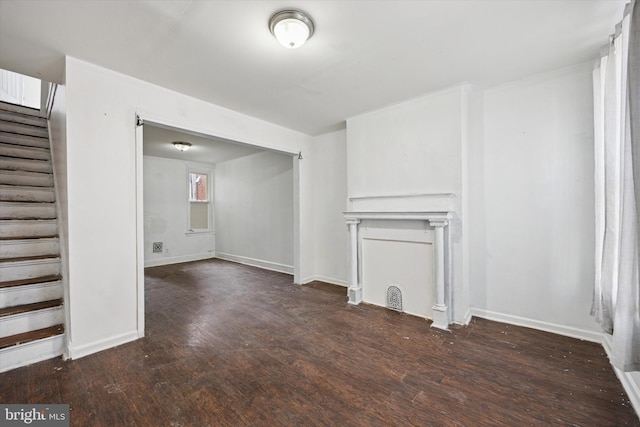 unfurnished living room with stairway, baseboards, and wood finished floors