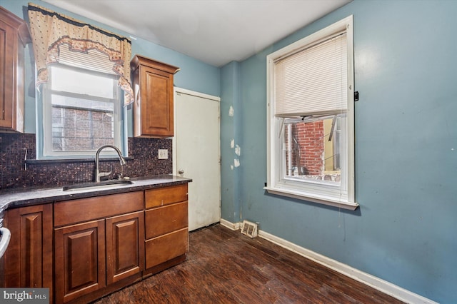 kitchen with a sink, tasteful backsplash, dark countertops, and dark wood-style floors