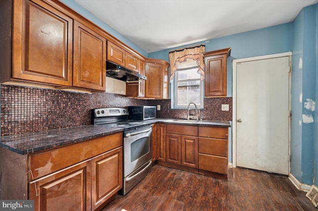 kitchen with under cabinet range hood, appliances with stainless steel finishes, brown cabinetry, and a sink