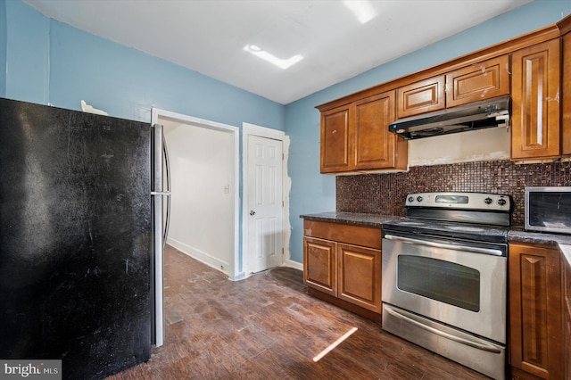 kitchen featuring dark countertops, brown cabinets, under cabinet range hood, and stainless steel appliances