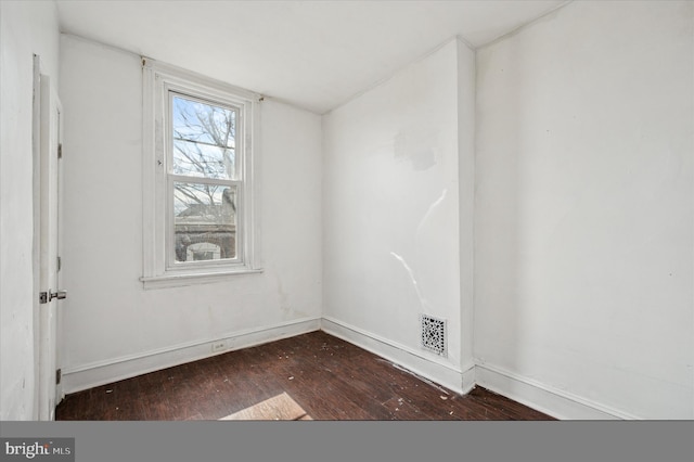 spare room with visible vents, baseboards, and wood-type flooring