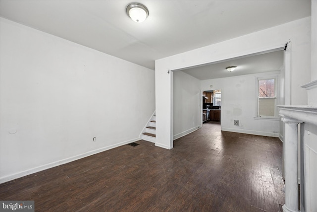 unfurnished living room with stairway, baseboards, and hardwood / wood-style floors