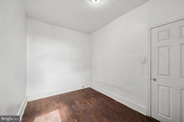 spare room with dark wood-type flooring and baseboards