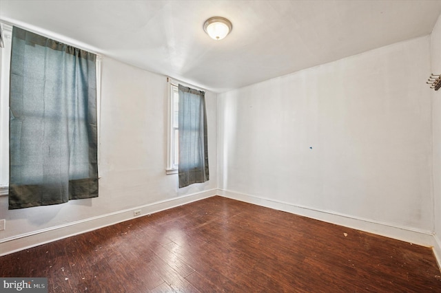 unfurnished room with dark wood-style floors and baseboards