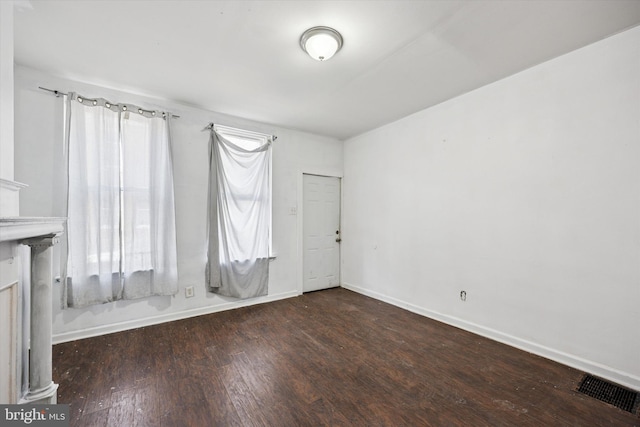 unfurnished room with a healthy amount of sunlight, wood finished floors, visible vents, and baseboards